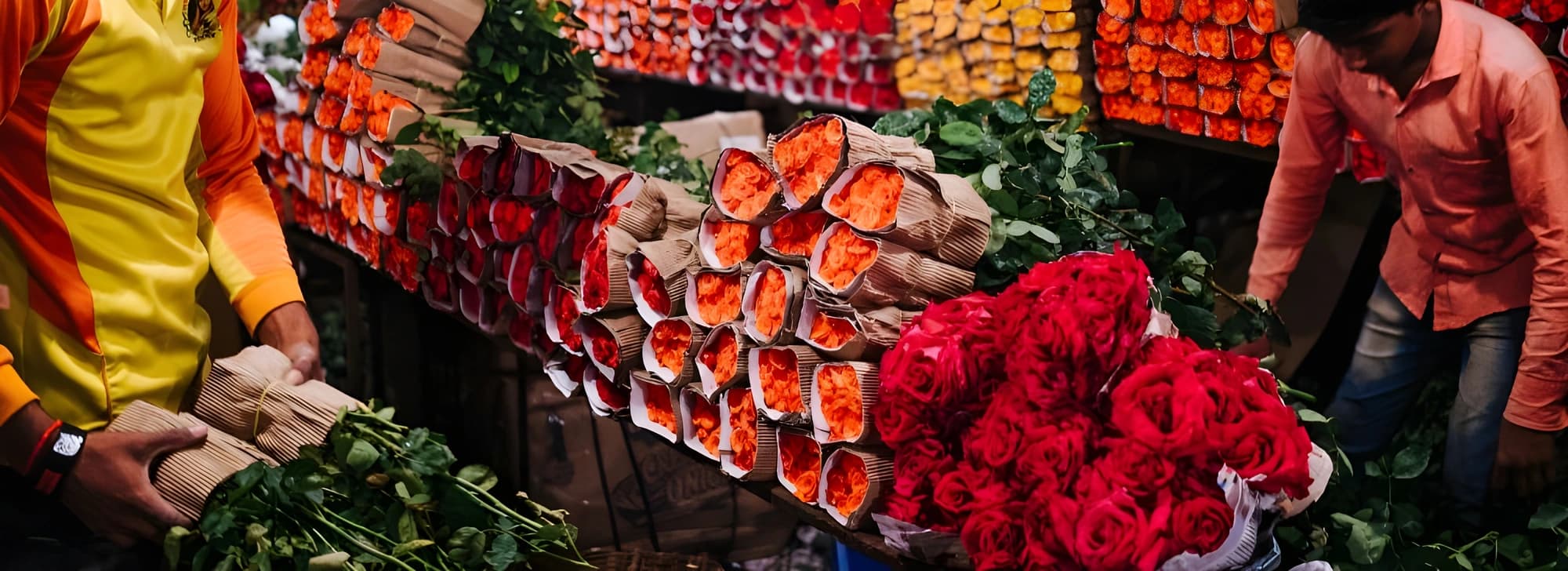 A man stands before a vibrant display of flowers, showcasing a variety of colors and arrangements in a floral shop.