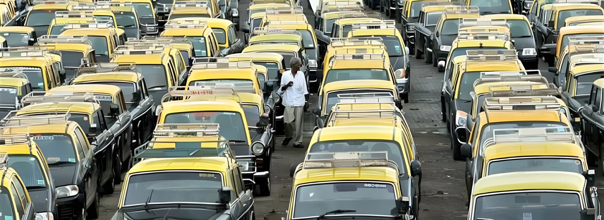 A crowded parking lot filled with numerous yellow taxis of Mumbai, showcasing their vibrant color and distinct shape.